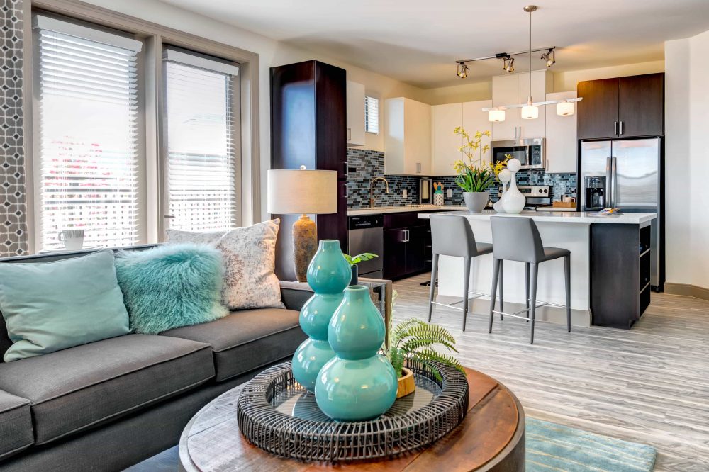 Apartments in Tempe AZ - Vela at Tempe Town Lake - Furnished Living Room With Stylish Furniture, a Coffee Table, and Windows With Blinds and Curtains