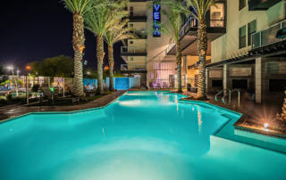 Apartments in Tempe - Vela at Tempe Town Lake - Outdoor Swimming Pool With Clear Water, Lounge Chairs, and Decorative Trees